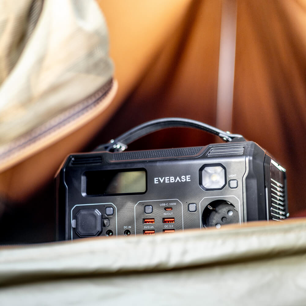 Using the EveBase Move 300 portable power station to recharge several electrical devices in a tent while camping. 